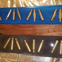 Brass cartridges displayed on blue walnut and black resin slabs