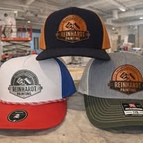 Three Reinhardt Painting hats with round leather patches in navy white blue red and heather olive