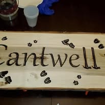 Rustic wood sign reading Cantwell with decorative paw prints